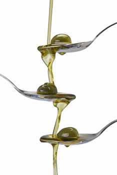 Olive oil poured into a spoon and falling from one to another spoon