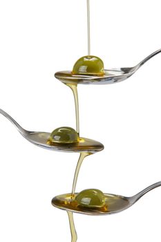 Olive oil poured into a spoon and falling from one to another spoon