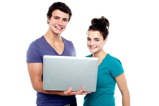 Charming teen couple holding a laptop isolate against white background