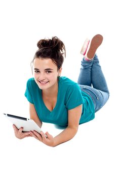 Pretty teenager watching movie on tablet pc. Lying on floor, studio shot
