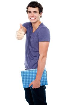 Fashionable youth with a notebook in hand showing thumbs up sign to the camera