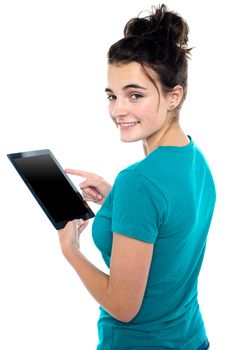 Trendy young casual girl operating tablet device while turning back and looking at you