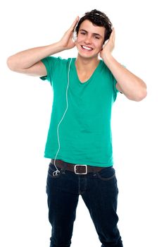 Cheerful guy enjoying loud music holding them tightly to ears