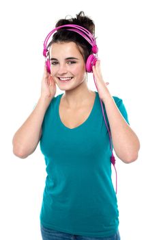 Cheerful pretty girl listening to music through headphones