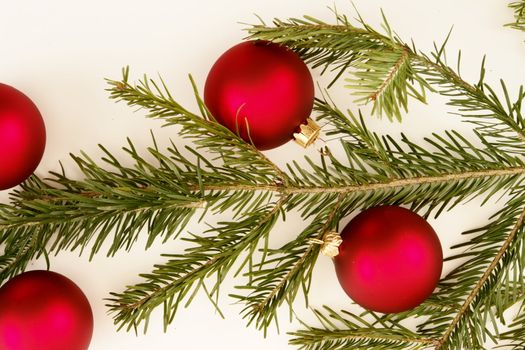 Border of red christmas garland with baubles and ribbons on white.