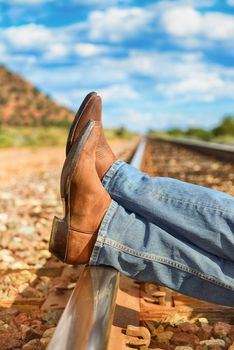 famous cow-boy boots and feets across train tracks 