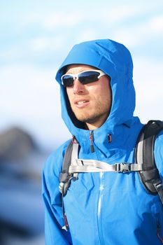 Hiking man - hiker portrait of young male hiker and climber in alpine wear hard shell jacket in high altitude mountain above the clouds.