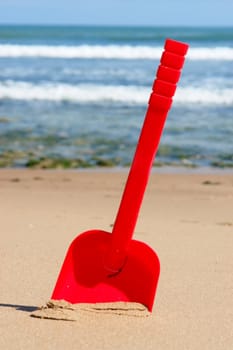 a red shovel at the beach on a sunny day