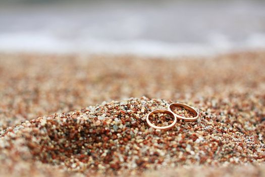 Wedding rings lie on the beach by the sea