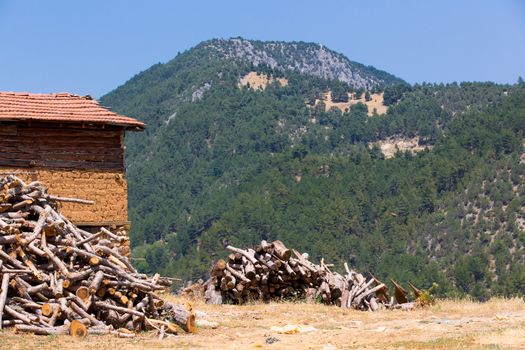 Wood covered adobe barn with woods of winter preperation. Scenic mountains at the background.