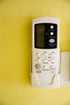 air conditioner remote control on yellow wall.