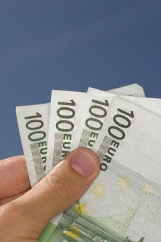man holding couple of 100 Euros against sky