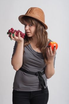 girl on a white background with grapes and apples in the hands of