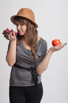 girl on a white background with grapes and apples in the hands of