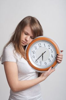 sleeping girl on a white background with a big clock in the hands of which 6.40 am