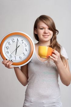 Smiling girl holding in one hand and watch while the other cup