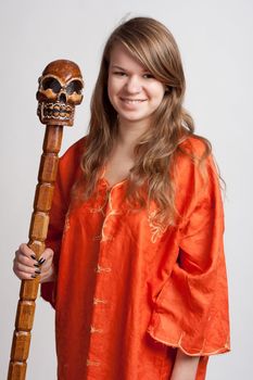 Girl in orange dress on a light background with a staff