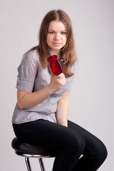 A girl in a bright red T-shirt and a glass sitting on a light background