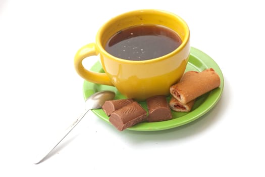 yellow cup of coffee with biscuits and chocolate on a white background