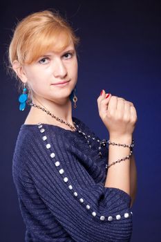 Red-haired girl in a blue blouse with a blue background with beads