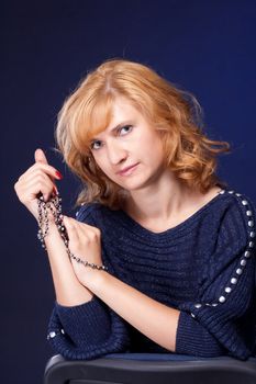 Red-haired girl in a blue blouse with a blue background with beads