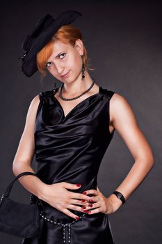 Red-haired girl in black clothes and hat on a black background