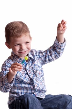Smiling boy with a lollipop in his hand on a light background