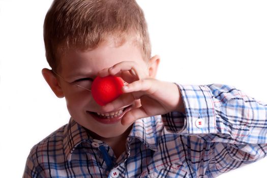 A little boy with a clown nose on a white background