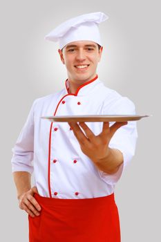 Young male chef in red apron against grey background