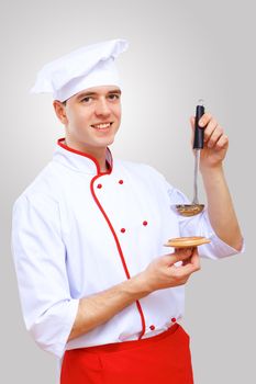 Young male chef in red apron against grey background