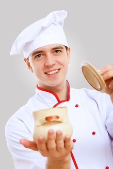 Young male chef in red apron against grey background