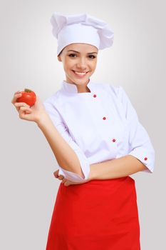 Young female chef in red apron against grey background