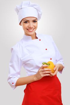 Young female chef in red apron against grey background