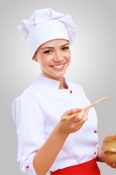 Young female chef in red apron against grey background