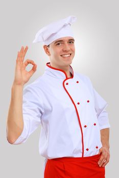 Young male chef in red apron against grey background