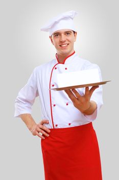 Young male chef in red apron against grey background