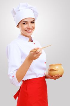 Young female chef in red apron against grey background