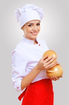 Young female chef in red apron against grey background