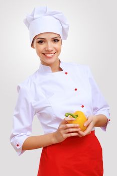 Young female chef in red apron against grey background