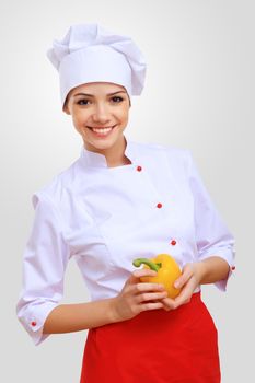 Young female chef in red apron against grey background