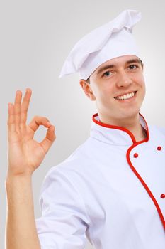 Young male chef in red apron against grey background