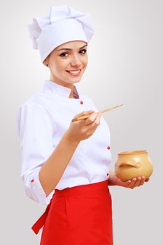 Young female chef in red apron against grey background