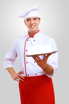 Young male chef in red apron against grey background