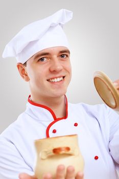 Young male chef in red apron against grey background