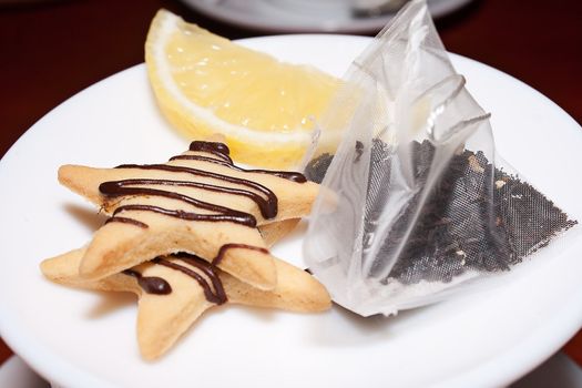 Cookies, lemon and tea bag lying on a saucer shot in cafe