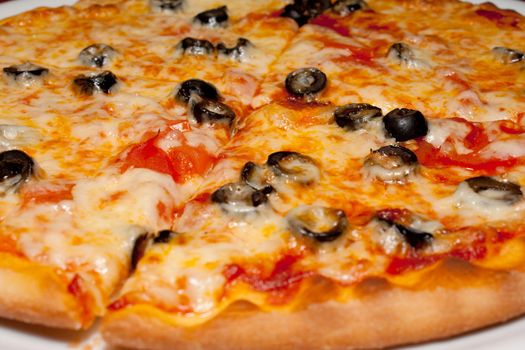 Pizza with black olives and melted cheese, close-up shooting in the cafe