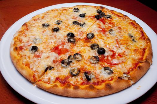 Pizza with black olives and melted cheese, close-up shooting in the cafe