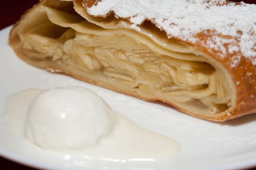 Apple pie with powdered sugar and ice cream at the forefront in the cafe shooting