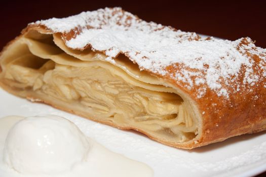 Apple pie with powdered sugar and ice cream at the forefront in the cafe shooting