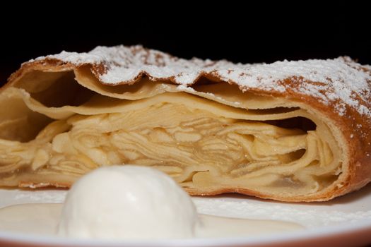 Apple pie with powdered sugar and ice cream at the forefront in the cafe shooting